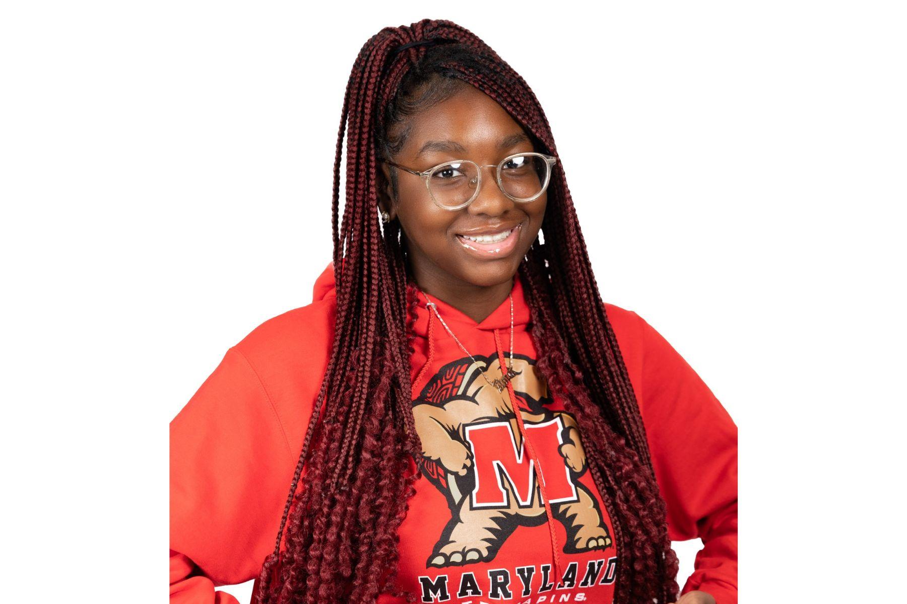 Queensley is wearing a Maryland sweatshirt and smiling at the camera